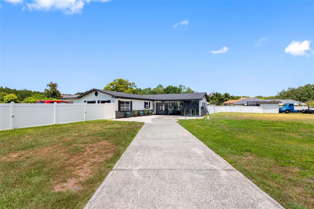 A single-story house with a white exterior, black trim, and a long concrete driveway — 5515 LAKE LE CLARE ROAD, LUTZ, FL