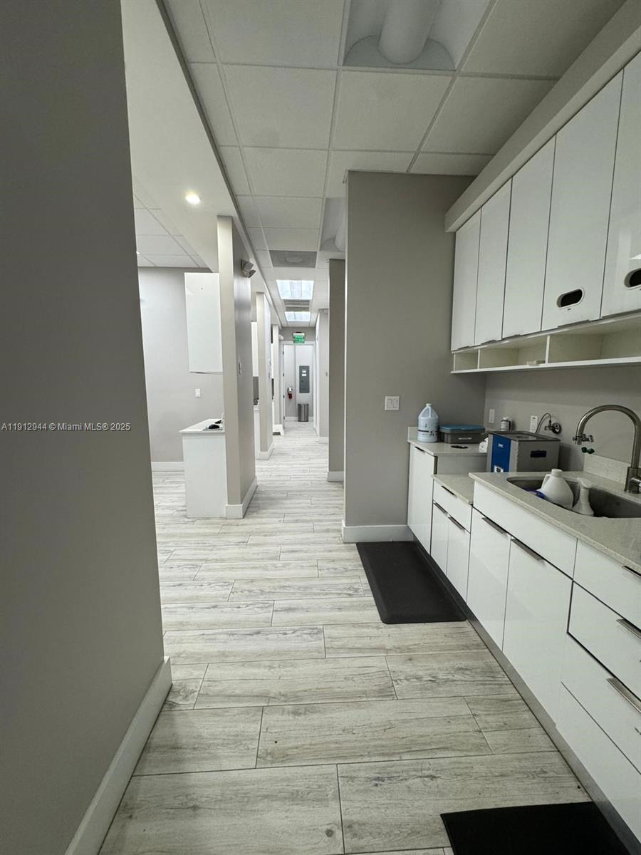 A narrow hallway leads to a clinical office space with white cabinetry and tile flooring — 9440 W Commercial Blvd, Sunrise FL 33351, SUNRISE, FL
