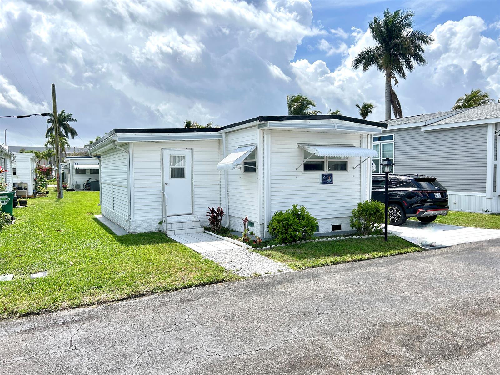 A white single-story mobile home features a small front porch, metal awnings, and a driveway — 3240 State Street, Hollywood FL 33021, HOLLYWOOD, FL
