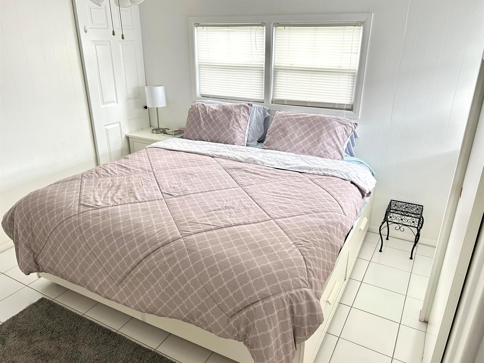 A bedroom features a bed with a patterned comforter, white tile flooring, and two windows — 3240 State Street, Hollywood FL 33021, HOLLYWOOD, FL