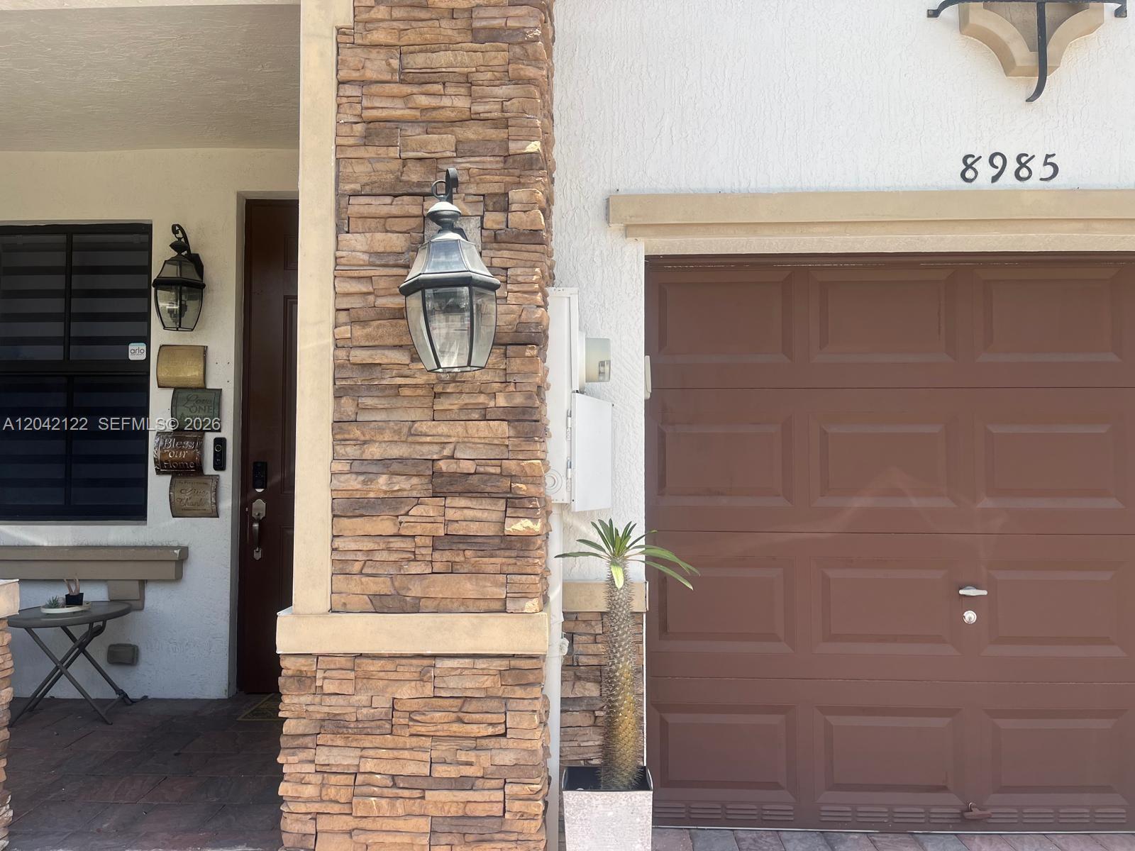 The exterior features a stone pillar, a brown garage door, and a front entryway — 8985 NW 98th Ave, Doral FL 33178, DORAL, FL