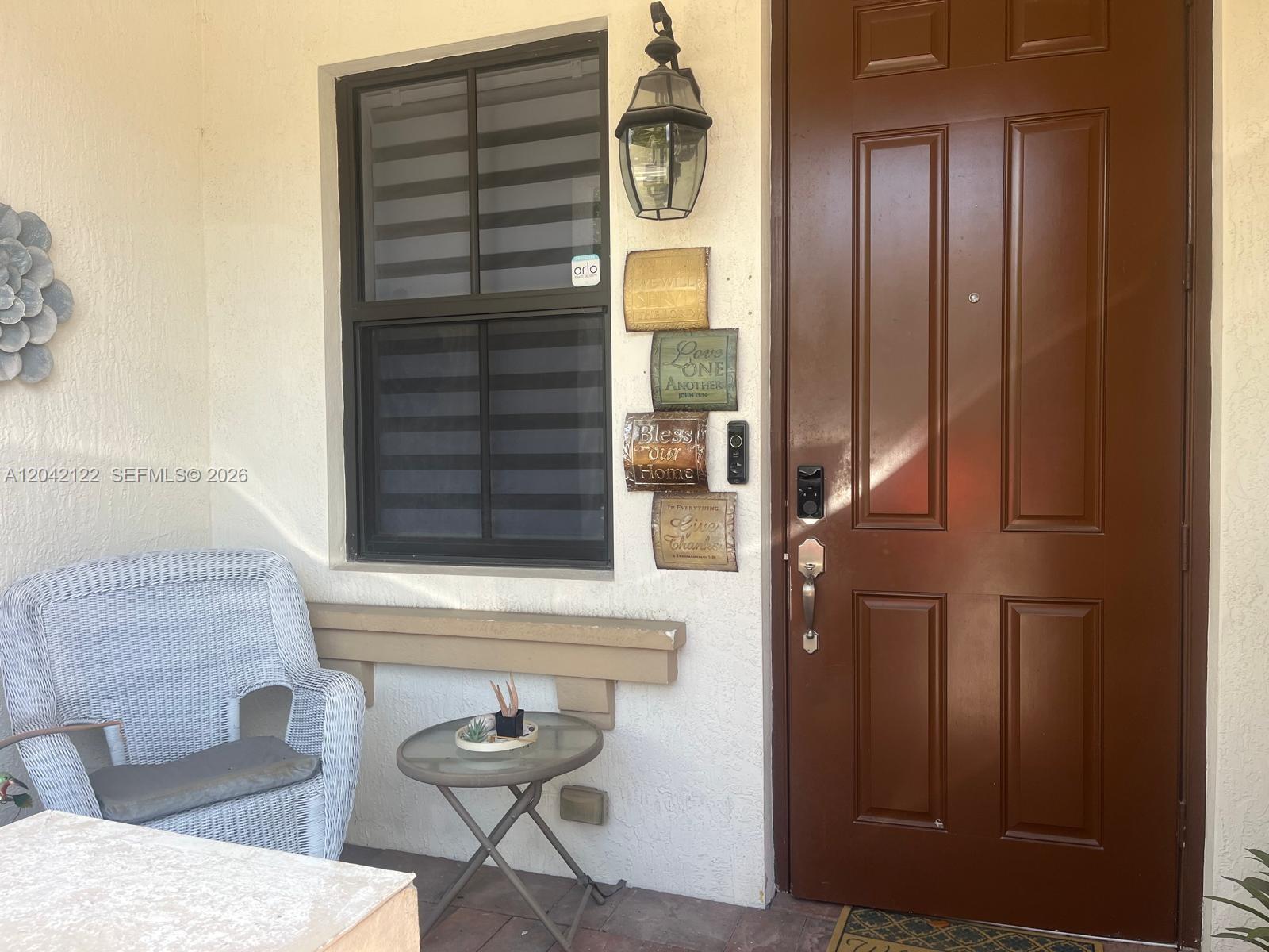 A front porch features a wicker chair, a small table, and a brown door — 8985 NW 98th Ave, Doral FL 33178, DORAL, FL