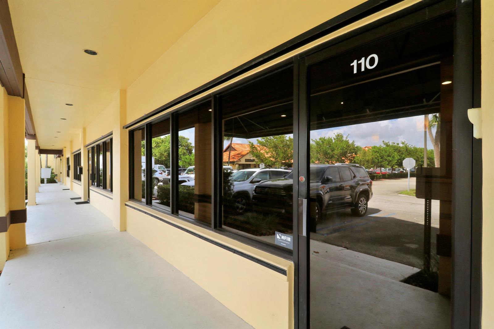 The exterior walkway of a commercial building features a glass storefront door labeled 110 — 725 N Hwy A1a # C110, Jupiter FL 33477, JUPITER, FL