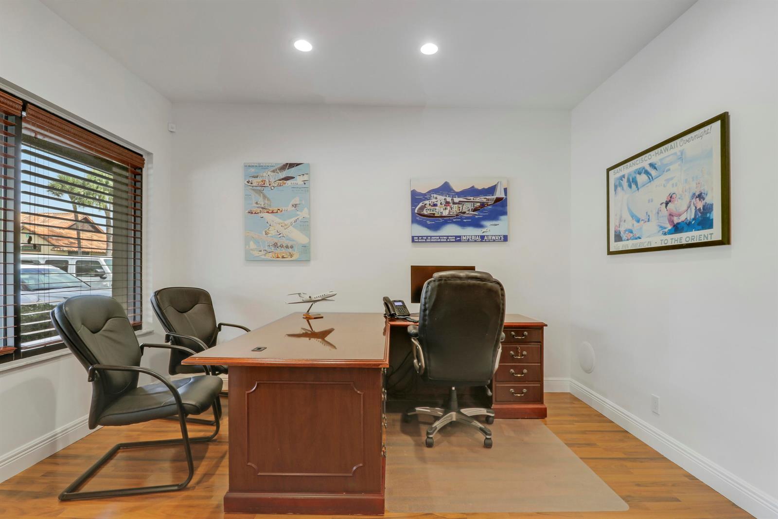 A home office features a wooden desk, three leather chairs, and aviation-themed wall art — 725 N Hwy A1a # C110, Jupiter FL 33477, JUPITER, FL