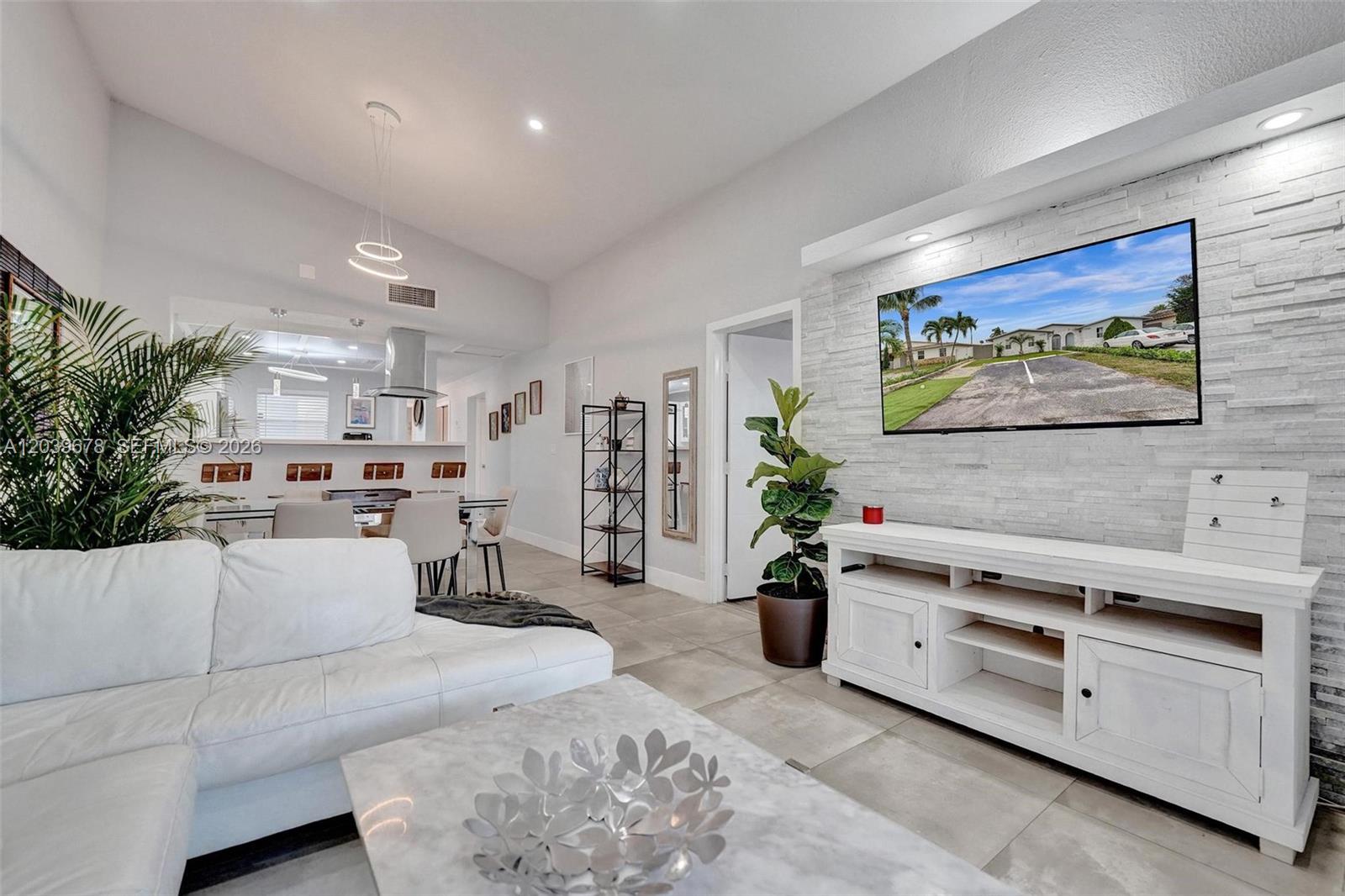 A living room features a white sectional sofa, a stone accent wall, and a television — 5535 SW 24th Ave, Dania Beach FL 33312, DANIA BEACH, FL