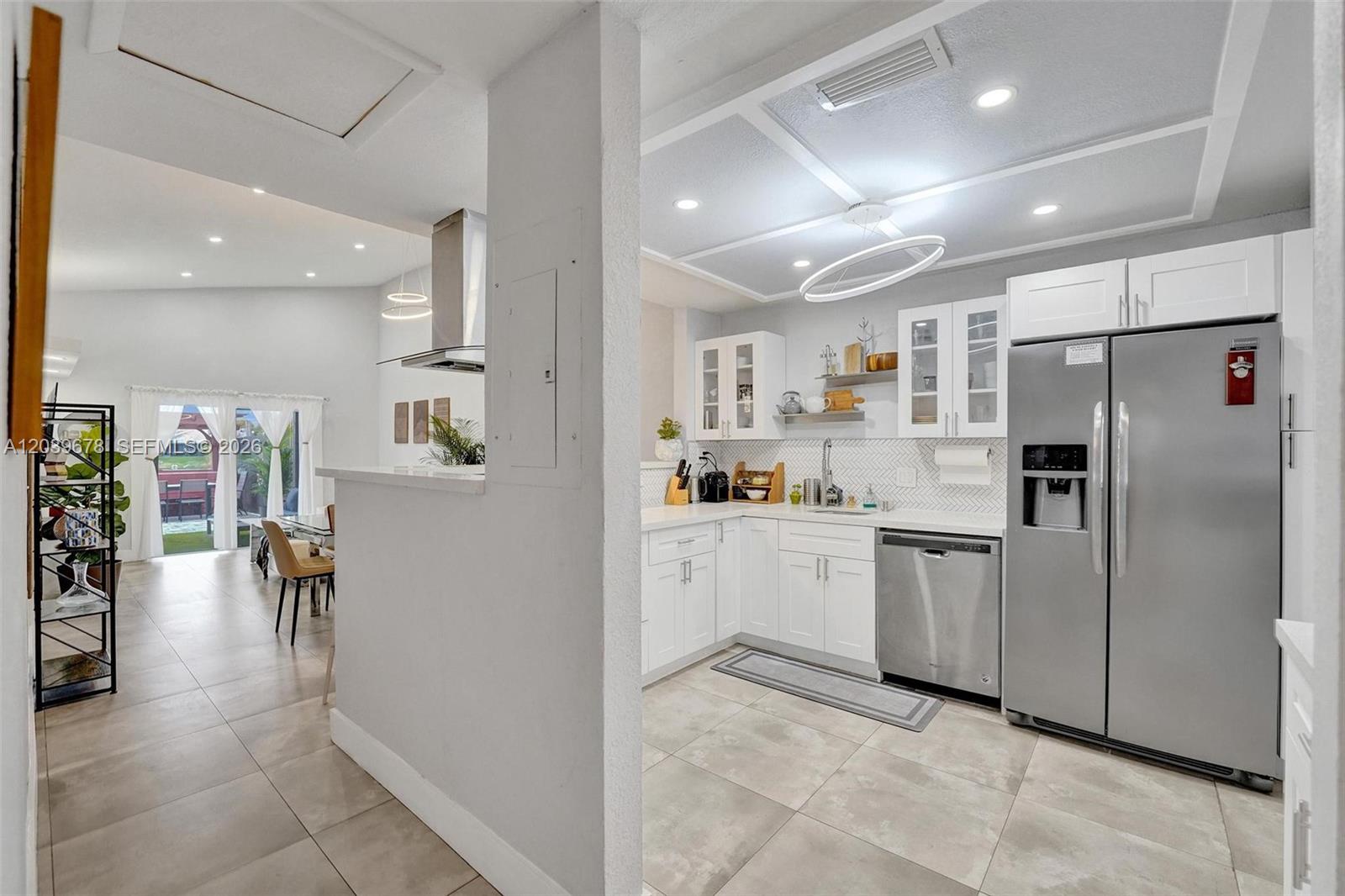 A bright kitchen with white cabinets and stainless steel appliances opens to a dining area — 5535 SW 24th Ave, Dania Beach FL 33312, DANIA BEACH, FL