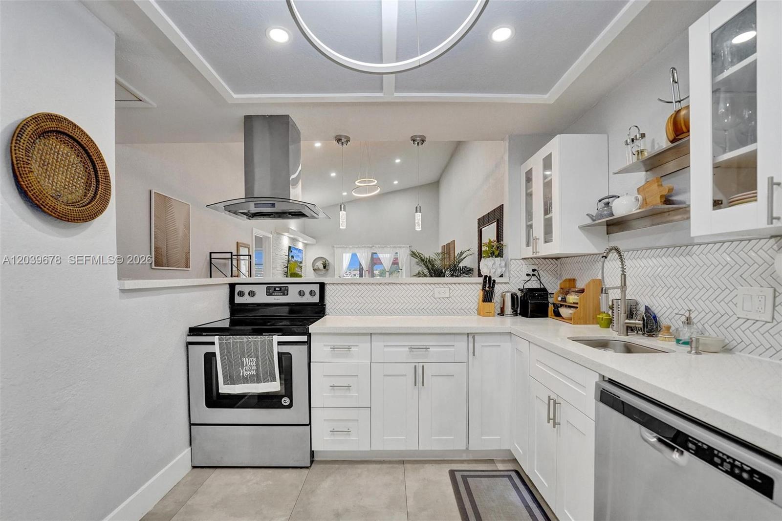 A white kitchen features stainless steel appliances, a herringbone backsplash, and an open-concept layout — 5535 SW 24th Ave, Dania Beach FL 33312, DANIA BEACH, FL