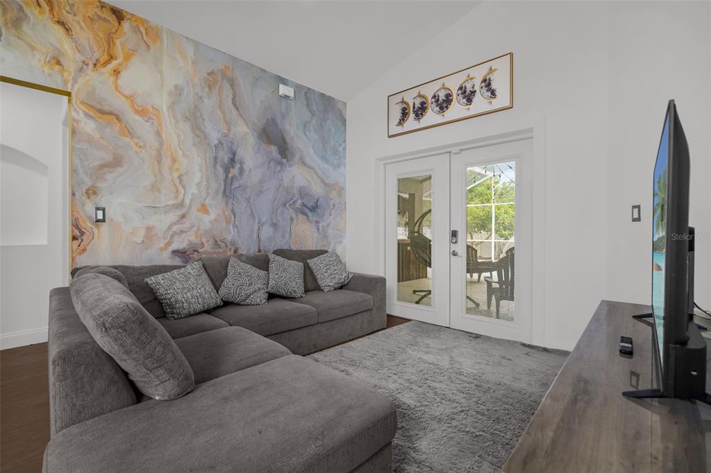 A living room features a large gray sectional sofa, a marble-patterned accent wall, and glass doors — 149 IMPERIAL OAK COURT, DAVENPORT, FL