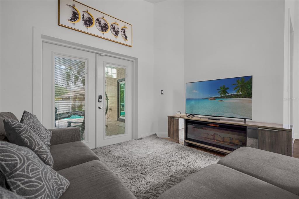 A living room features a gray sectional, a fireplace console, and glass doors to a patio — 149 IMPERIAL OAK COURT, DAVENPORT, FL