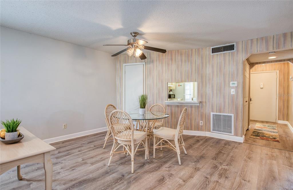 A dining area features a glass-topped table, wicker chairs, wood-look flooring, and striped wallpaper — 2206 CORDOVA GREEN, SEMINOLE, FL