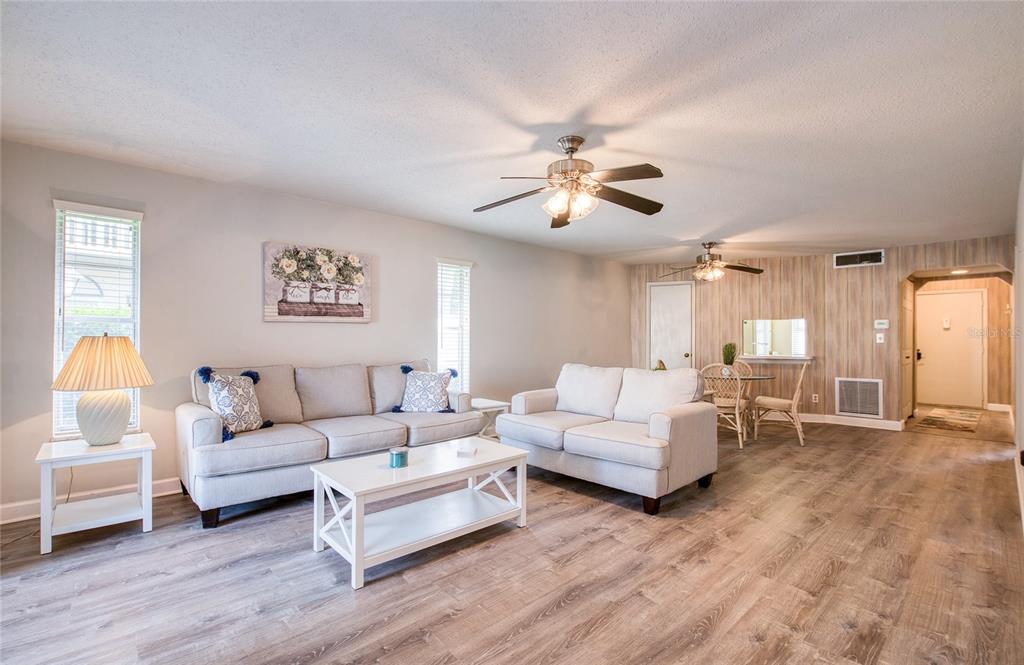 A living room features light gray walls, wood-look flooring, two sofas, and two ceiling fans — 2206 CORDOVA GREEN, SEMINOLE, FL