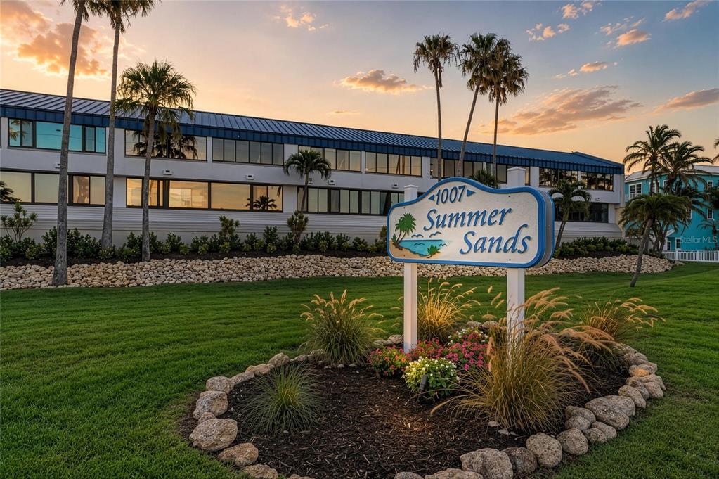 A sign for Summer Sands stands on a grassy lawn in front of a building — 1007 GULF DRIVE N UNIT 208, BRADENTON BEACH, FL