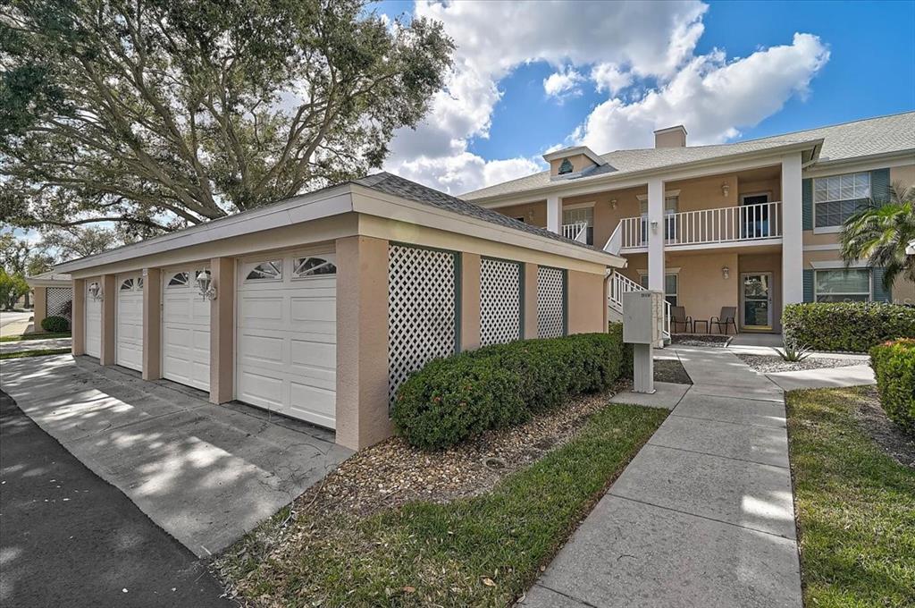 A row of garages sits beside a two-story apartment building with a concrete walkway — 4215 CADDIE DRIVE E UNIT 102, BRADENTON, FL