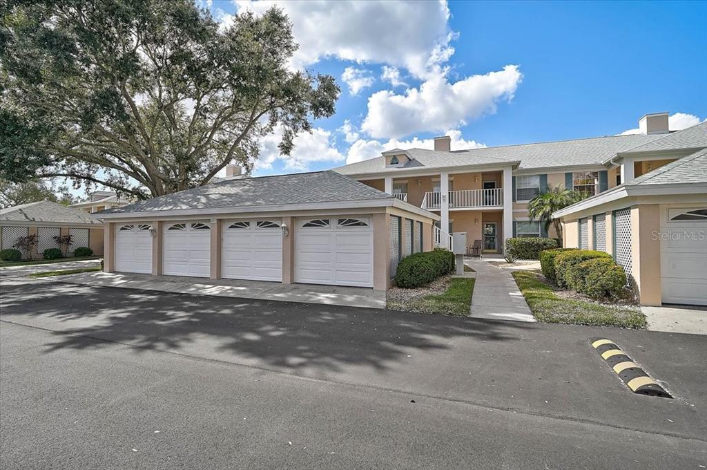 A multi-unit residential building features a row of white garage doors and a walkway — 4215 CADDIE DRIVE E UNIT 102, BRADENTON, FL