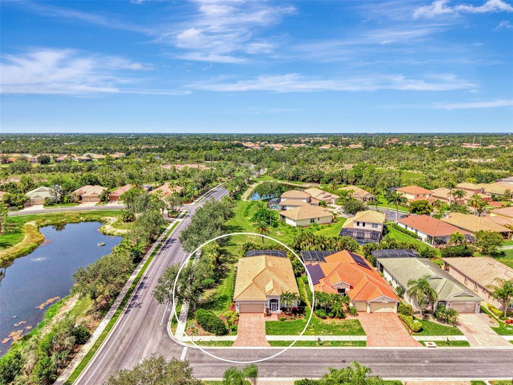 An aerial view shows a single-story house with a tan roof and a paved driveway — 11783 PUMA PATH, VENICE, FL