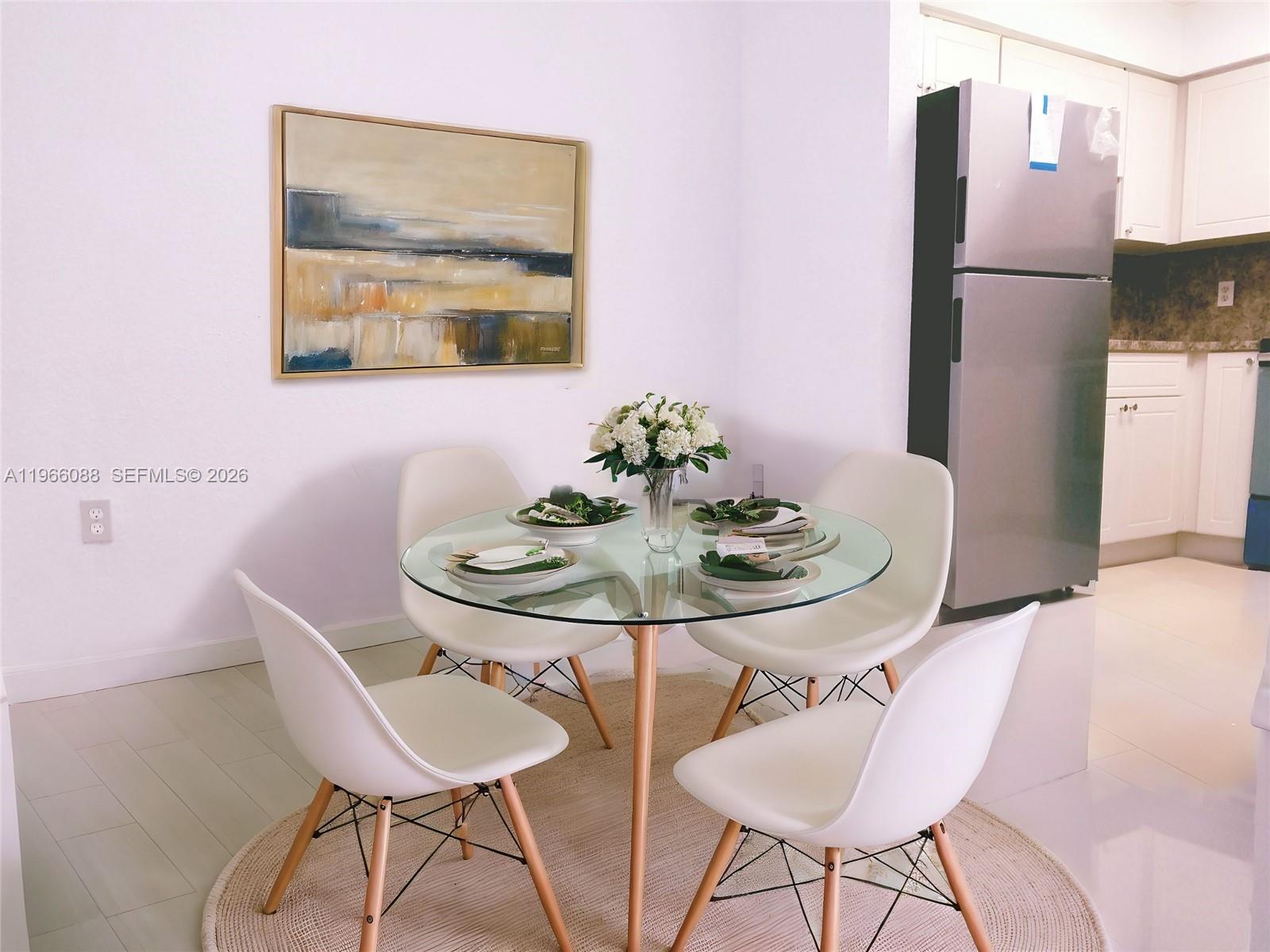 A dining area features a glass-topped table with four white chairs on a round rug — 5748 W 26th Ave # 5748, Hialeah FL 33016, HIALEAH, FL