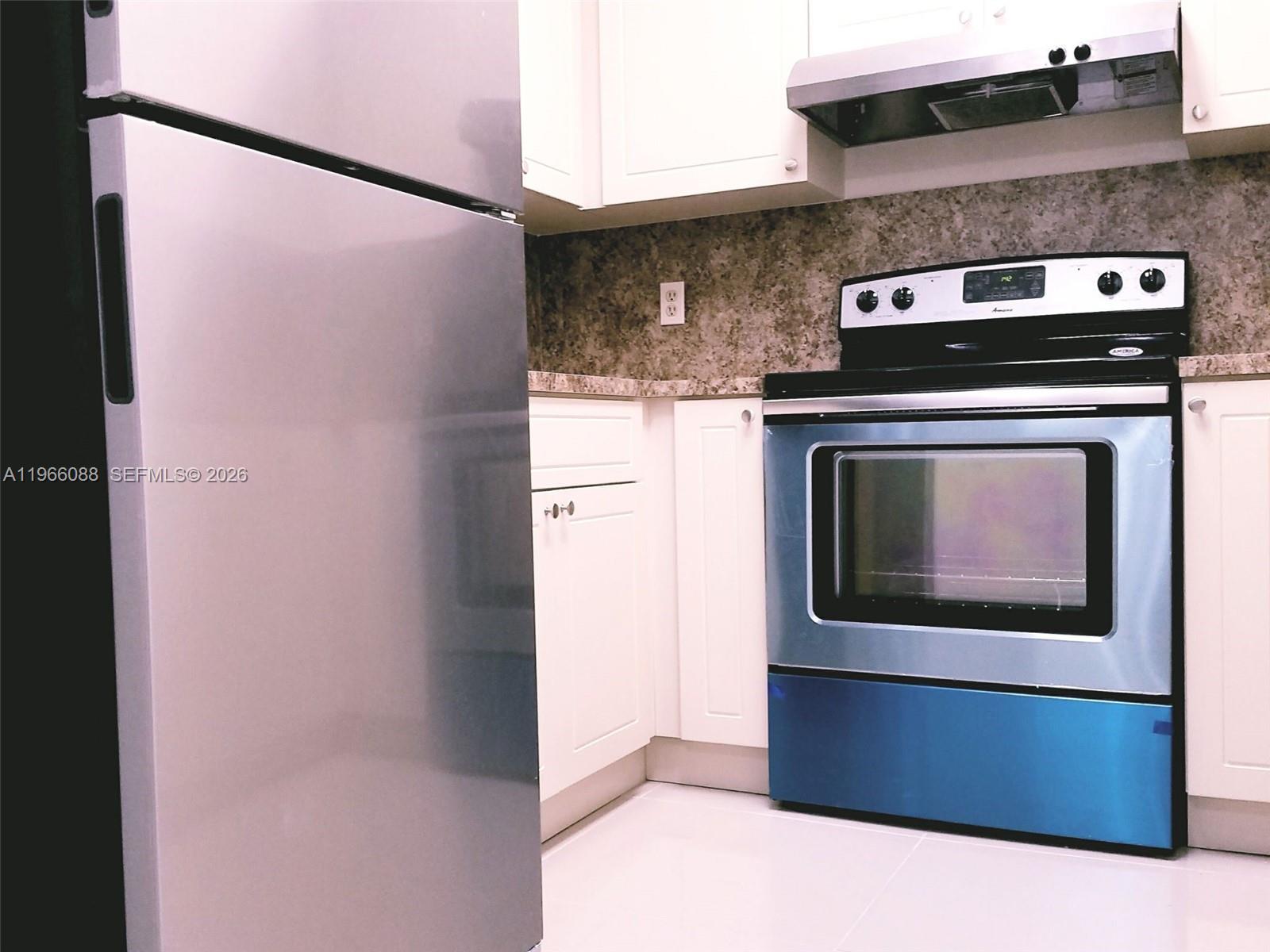 A kitchen features white cabinets, stainless steel appliances, and a speckled stone countertop — 5748 W 26th Ave # 5748, Hialeah FL 33016, HIALEAH, FL