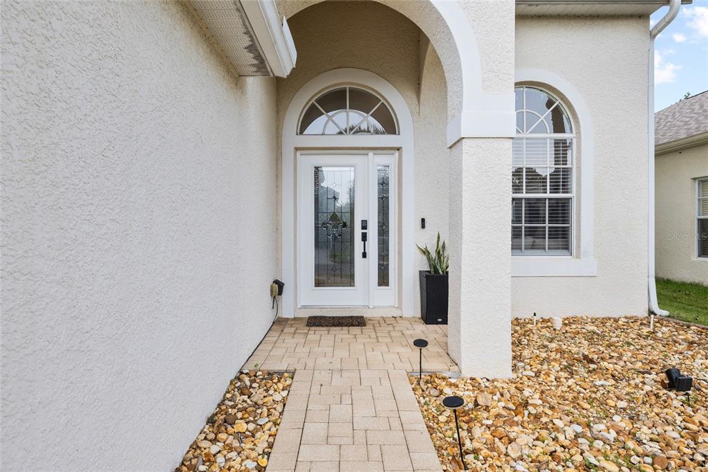 The exterior entryway features a white arched front door with glass panels and stone pavers — 3602 MORGANS BLUFF COURT, LAND O LAKES, FL