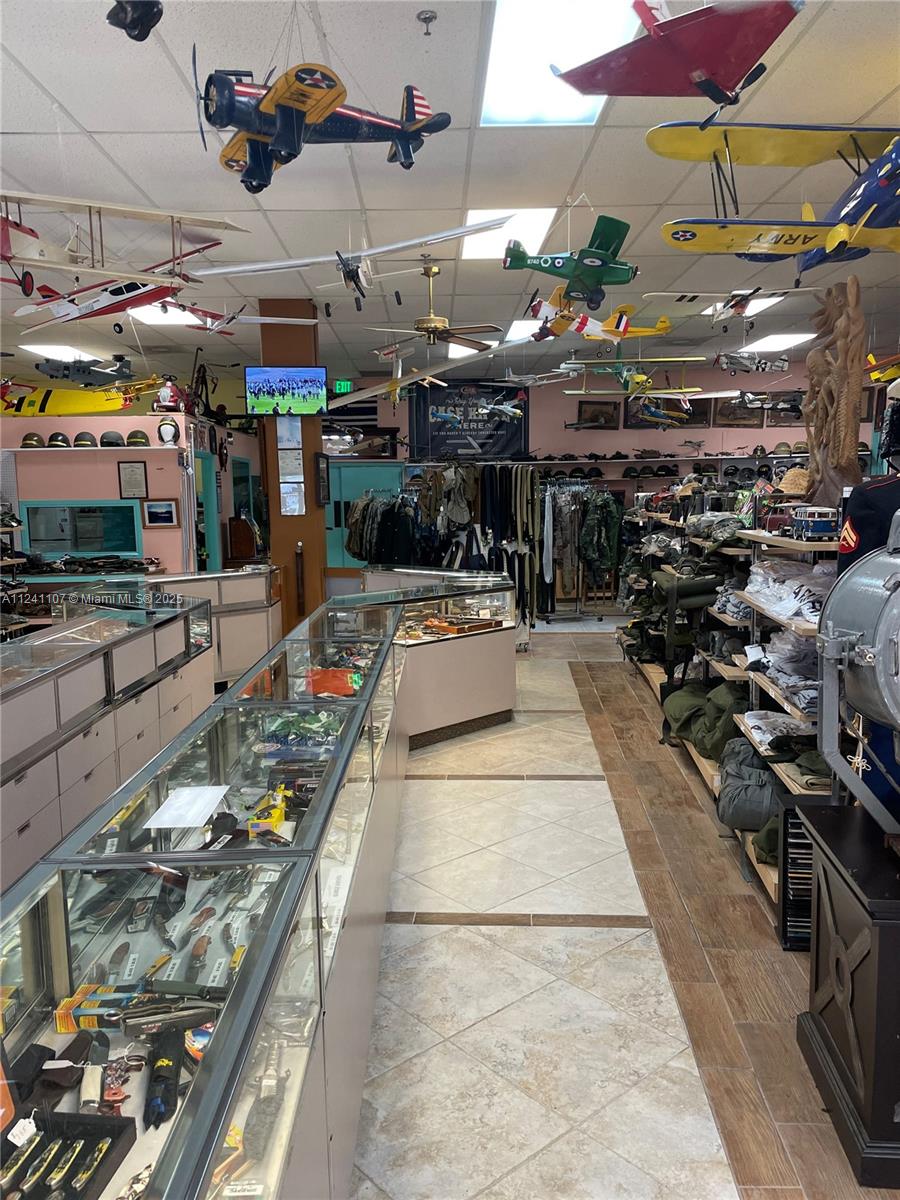 A retail store interior features glass display cases, shelves of merchandise, and model airplanes suspended overhead — 755 NW Federal Hwy, Stuart FL 34997, STUART, FL