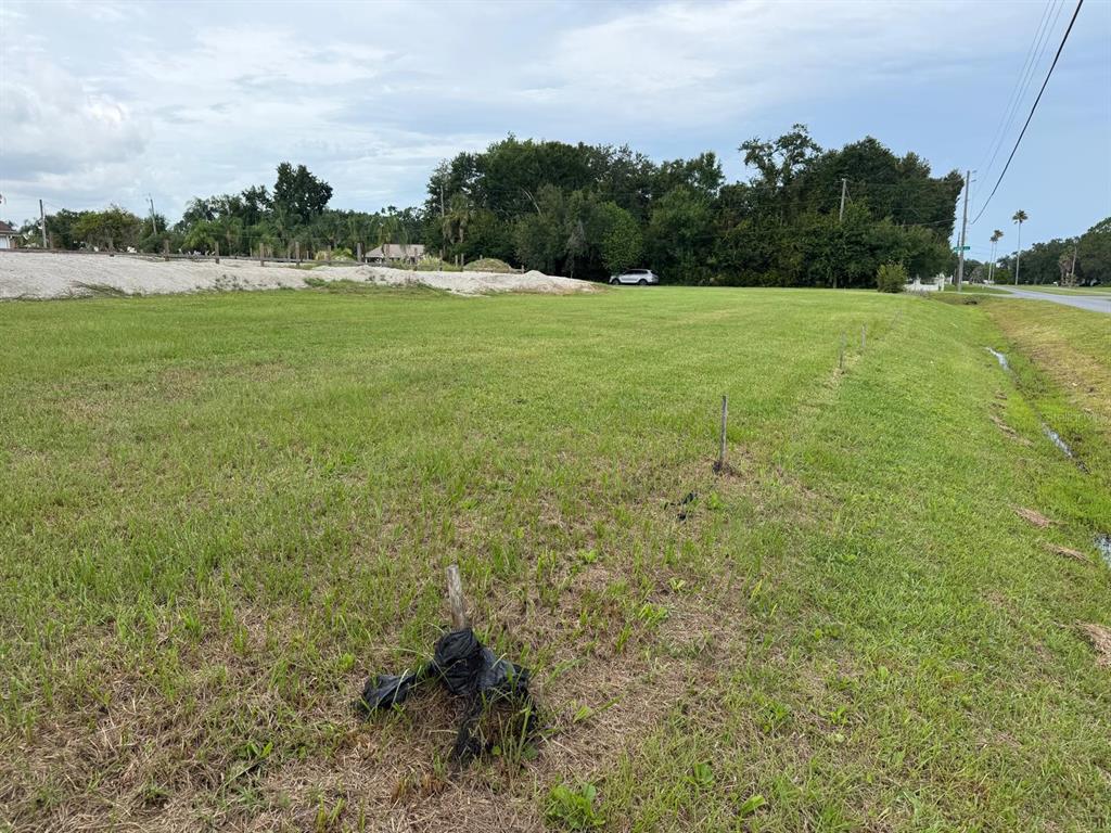 A grassy, vacant lot features several wooden survey stakes and a drainage ditch along the road — 2965 LUCKY CIRCLE, KISSIMMEE, FL