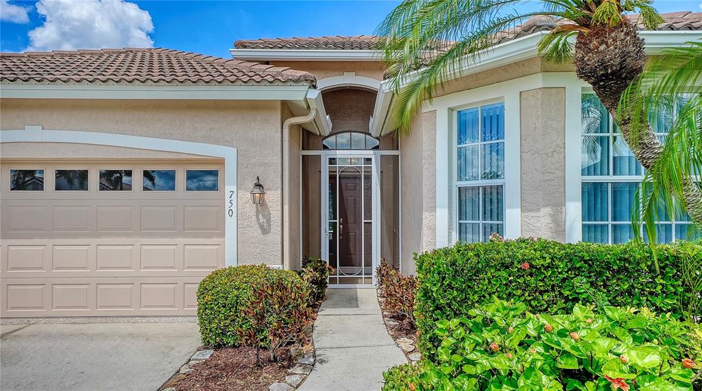 The exterior of a beige stucco house features a garage, front entryway, and landscaping — 750 BACK NINE DRIVE, VENICE, FL
