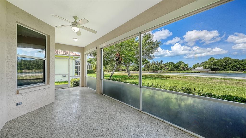 A screened-in patio with a ceiling fan, speckled concrete flooring, and a view of water — 750 BACK NINE DRIVE, VENICE, FL
