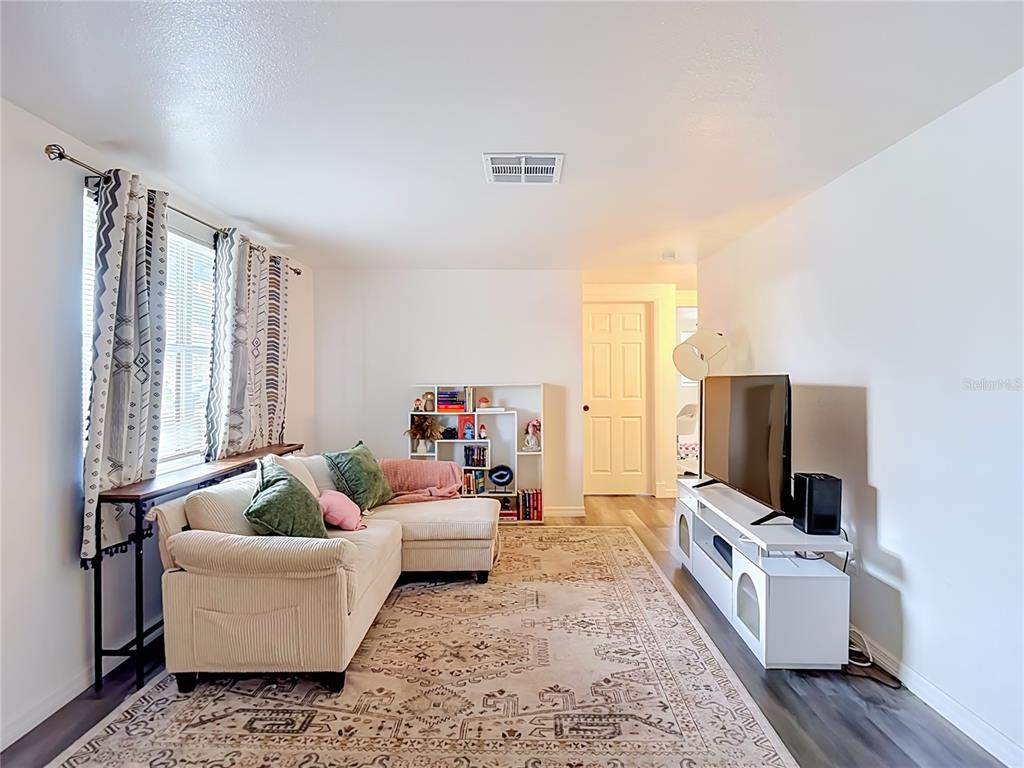 A living room features a beige sectional sofa, a white media console, and a patterned rug — 2036 SHANNON DRIVE, HOLIDAY, FL