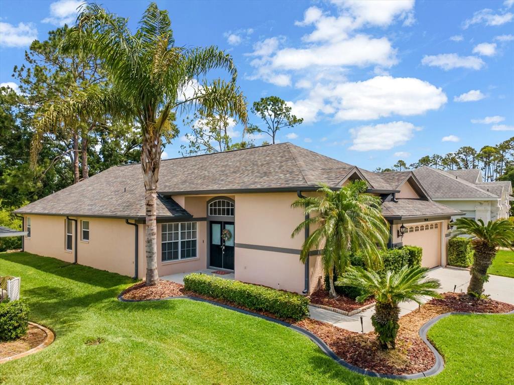 A single-story house with a peach-colored exterior, dark trim, and a palm-lined front lawn — 9631 OAKWOOD HILLS COURT, NEW PORT RICHEY, FL