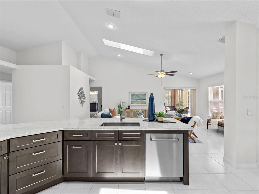 A kitchen island with a stainless steel dishwasher and sink faces an open living area — 9631 OAKWOOD HILLS COURT, NEW PORT RICHEY, FL