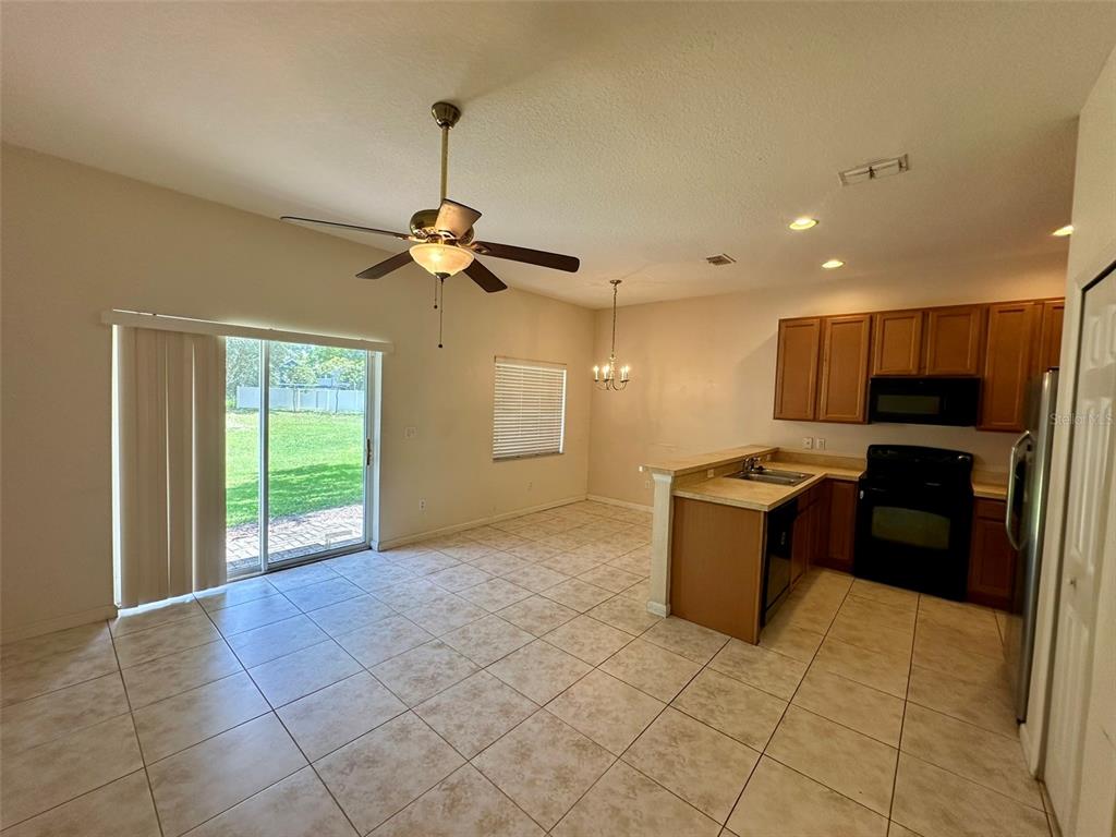 An open-concept kitchen and dining area features tile flooring, wood cabinets, and a sliding door — 3880 WHITE BIRCH RUN, WINTER SPRINGS, FL