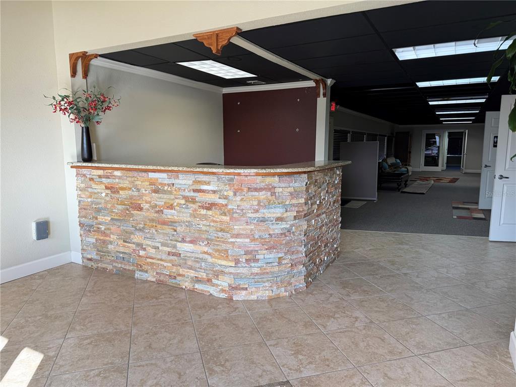 A reception area features a stone-faced desk, tile flooring, and a dark drop ceiling — 221 W STATE ROAD 434, LONGWOOD, FL