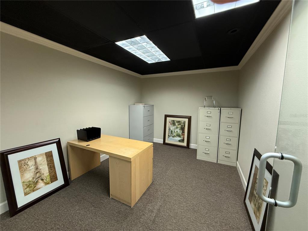 An office space features a light wood desk, filing cabinets, and framed artwork on carpet — 221 W STATE ROAD 434, LONGWOOD, FL