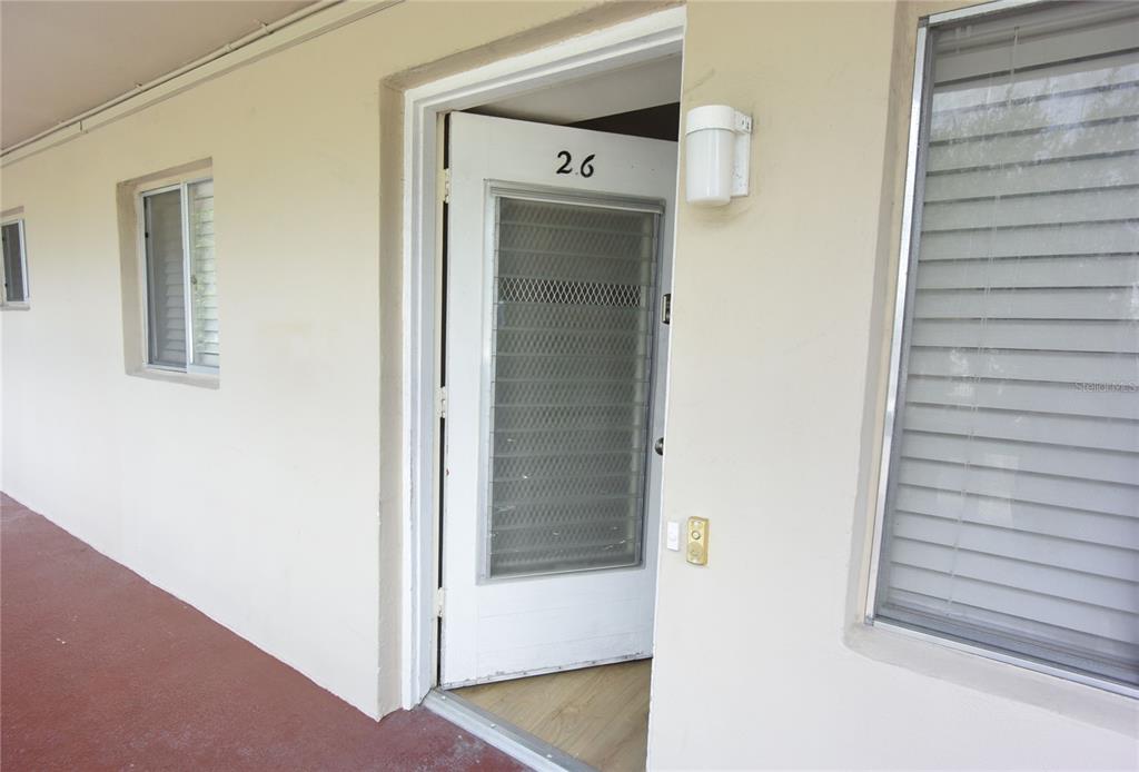 A view of an exterior apartment door numbered 26 with a screen door and windows — 3751 S SCHOOL AVENUE UNIT 26, SARASOTA, FL