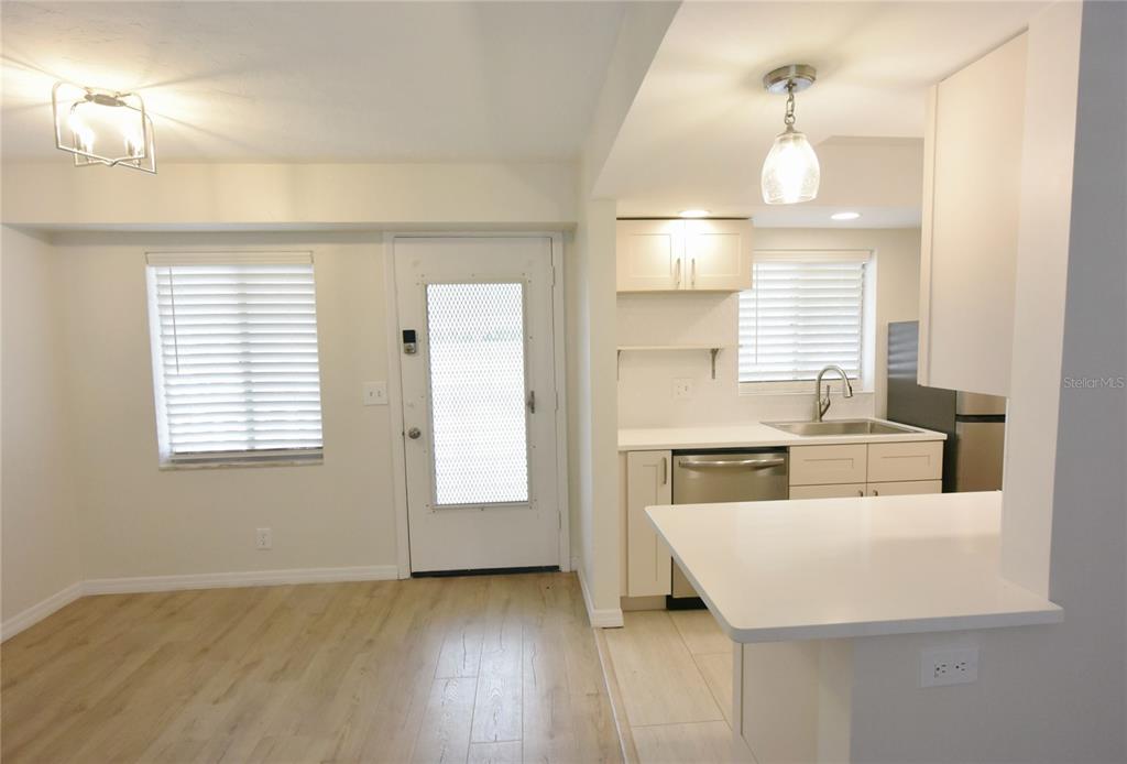 A kitchen with white cabinets and a breakfast bar opens into a dining area — 3751 S SCHOOL AVENUE UNIT 26, SARASOTA, FL