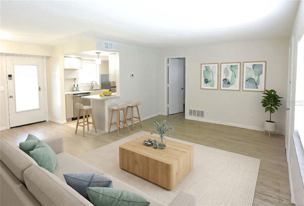 A living room with light wood flooring, a beige sofa, and a kitchen breakfast bar — 3751 S SCHOOL AVENUE UNIT 26, SARASOTA, FL