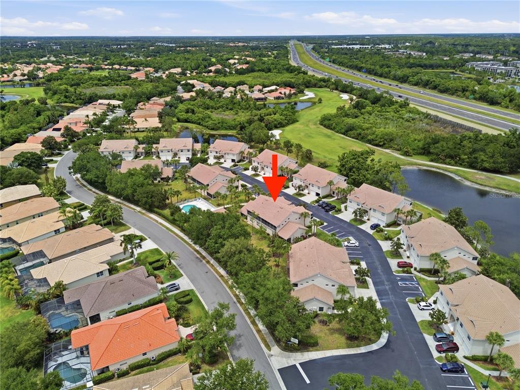 A two-story tan stucco townhouse features a tile roof, two garage doors, and stairs — 7660 SWEETBAY CIRCLE, BRADENTON, FL