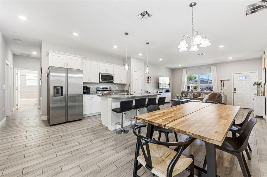 An open-concept kitchen and dining area features white cabinetry, stainless steel appliances, and tile flooring — 638 GULL DRIVE, KISSIMMEE, FL
