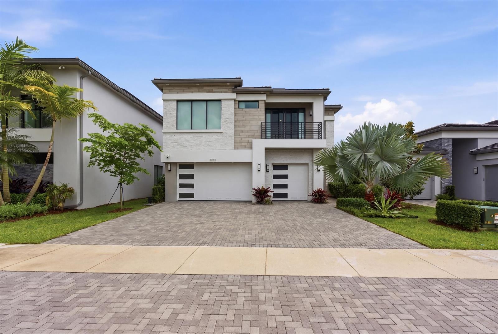 A two-story modern house features a paved driveway, two garage doors, and a balcony — 8568 Crystal Downs Avenue, Boca Raton FL 33434, BOCA RATON, FL