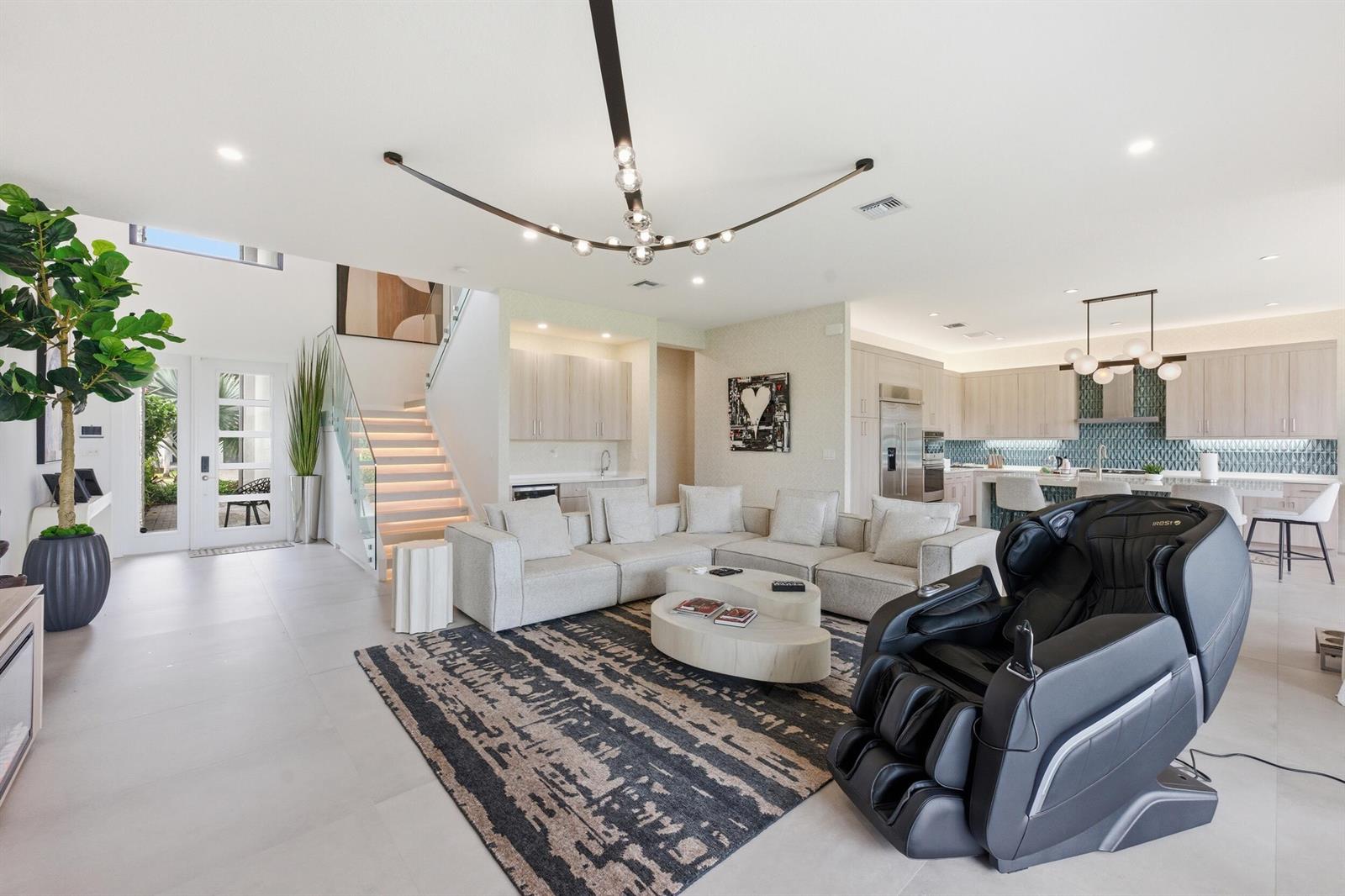 A modern open-concept living room features a large sectional sofa, massage chair, and floating staircase — 8568 Crystal Downs Avenue, Boca Raton FL 33434, BOCA RATON, FL