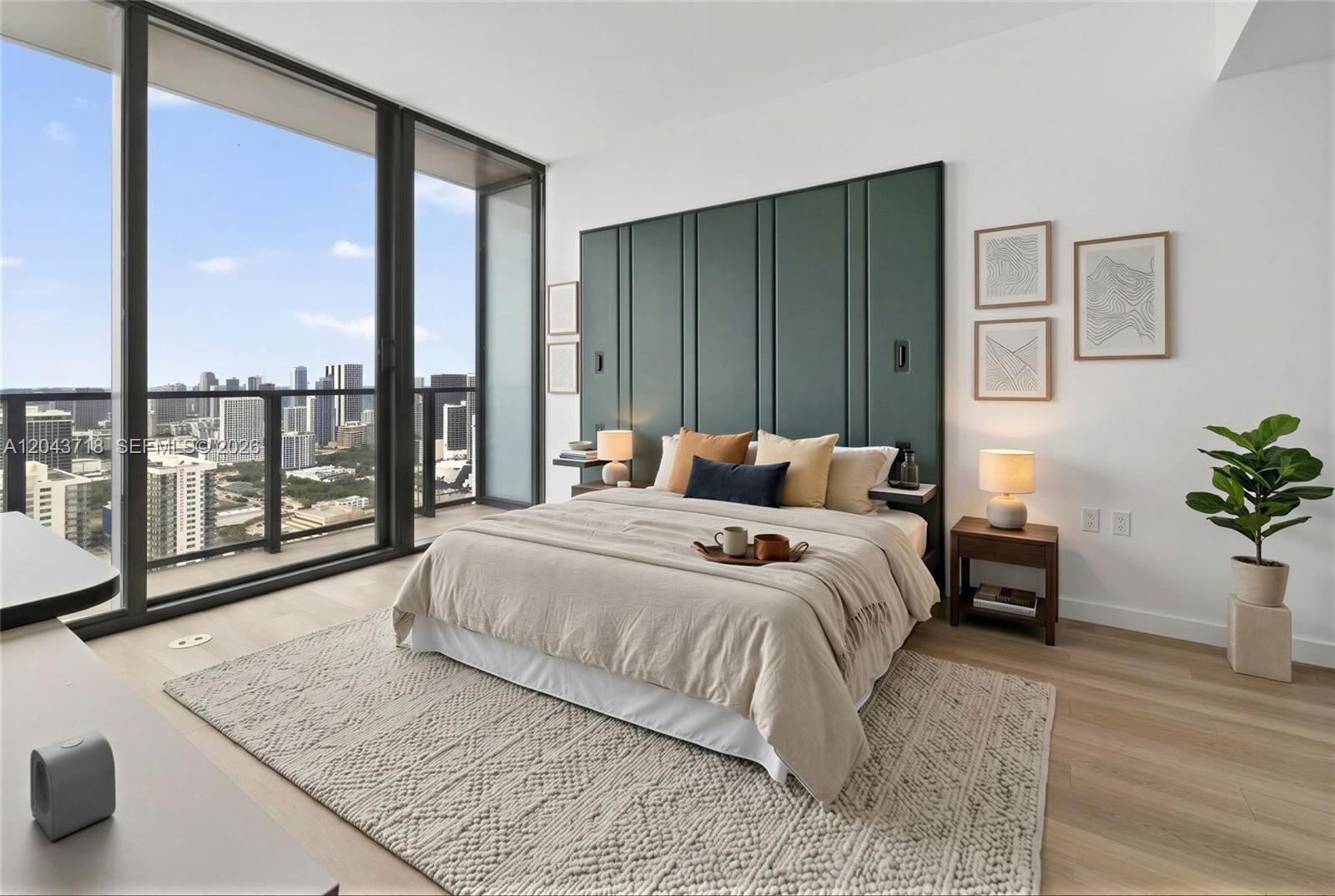 A modern bedroom features a green paneled headboard, a beige bed, and floor-to-ceiling city views — 20 NE 11th # 4701, Miami FL 33132, MIAMI, FL
