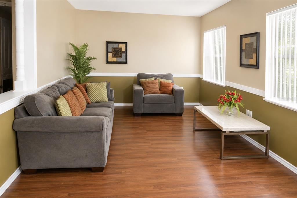 A living room features gray furniture, wood-look flooring, two-tone walls, and a marble-topped coffee table — 655 PINECREST DRIVE, BARTOW, FL