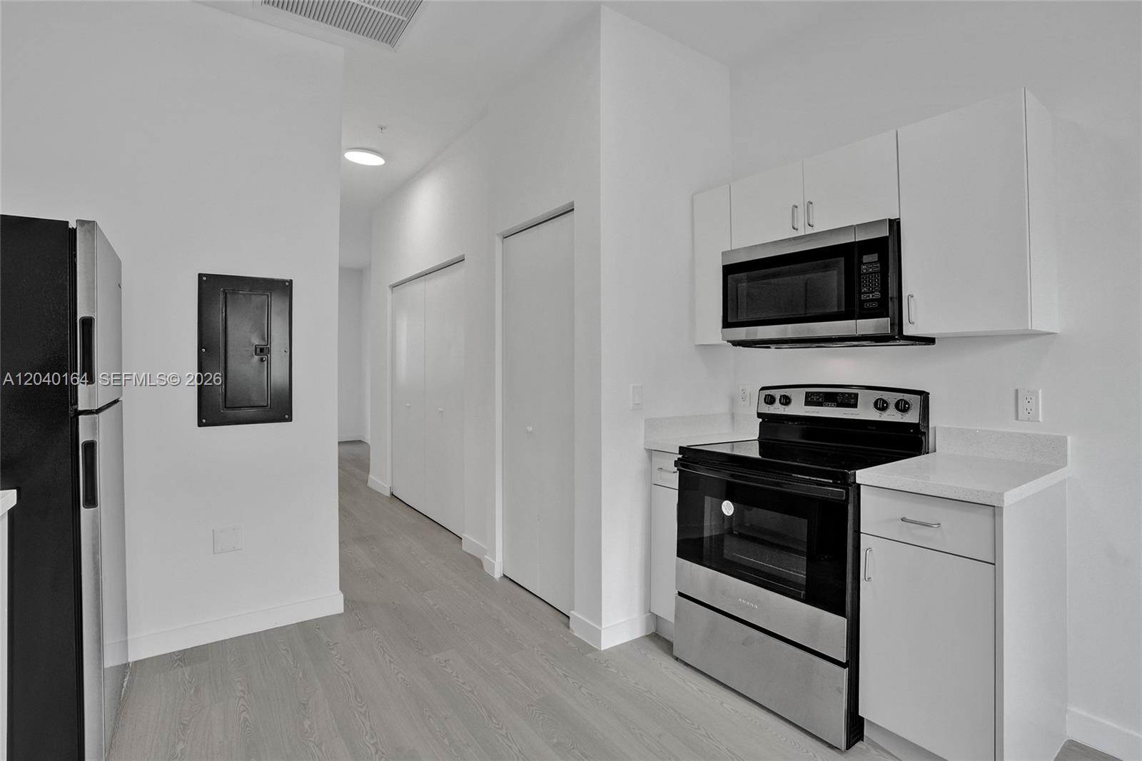 A kitchen features white cabinets, stainless steel appliances, and light wood-look flooring — 1567 NW 1st St # 5, Miami FL 33125, MIAMI, FL