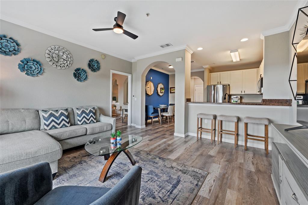 A living room with a gray sectional sofa, a glass coffee table, and an open kitchen — 14200 AVALON ROAD UNIT 409, WINTER GARDEN, FL