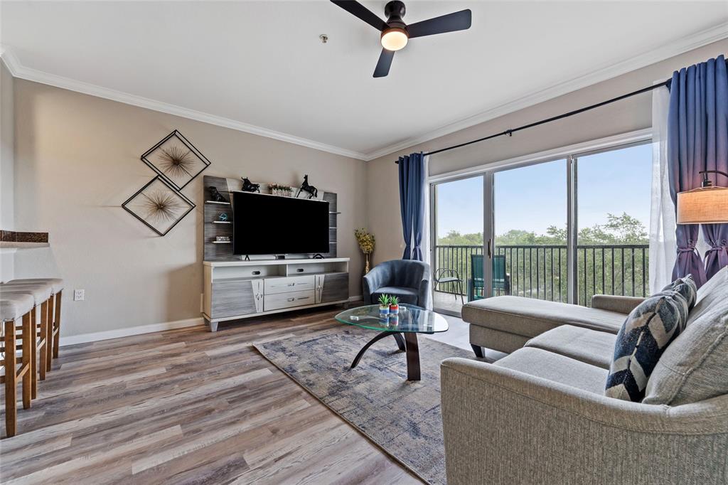 A living room features wood-look flooring, a sectional sofa, a television console, and a balcony — 14200 AVALON ROAD UNIT 409, WINTER GARDEN, FL