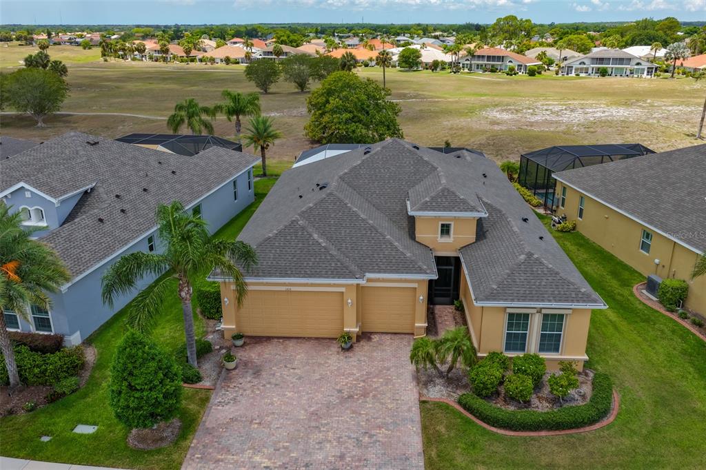 An aerial view shows a tan single-story house with a brick driveway and shingled roof — 1719 PACIFIC DUNES DR, SUN CITY CENTER, FL