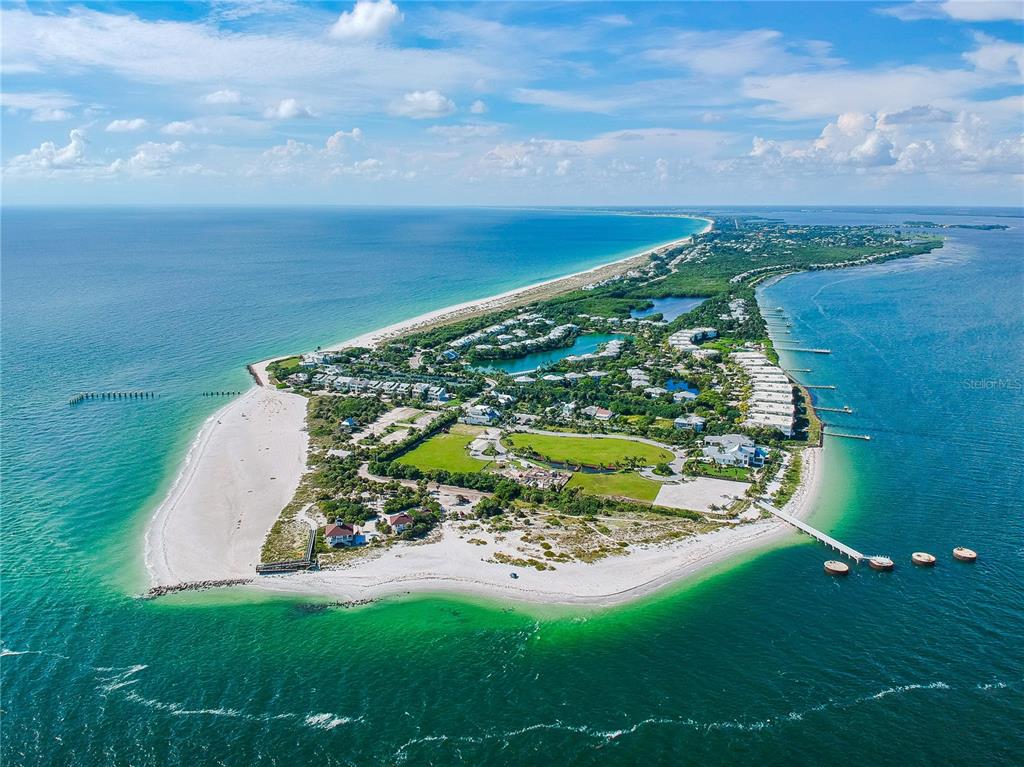 An aerial view of a coastal peninsula featuring sandy beaches, residential buildings, and a pier — 285 ROTONDA BOULEVARD W, ROTONDA WEST, FL