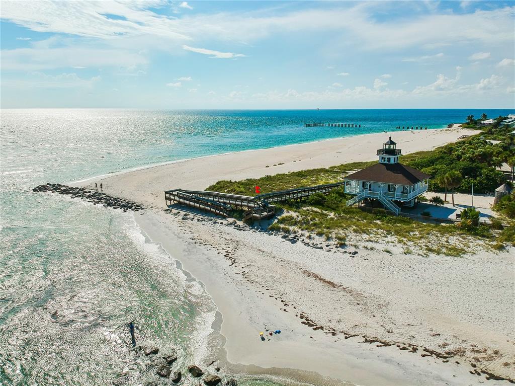 An elevated beach house with a lighthouse-style cupola sits near a wooden boardwalk and shoreline — 285 ROTONDA BOULEVARD W, ROTONDA WEST, FL