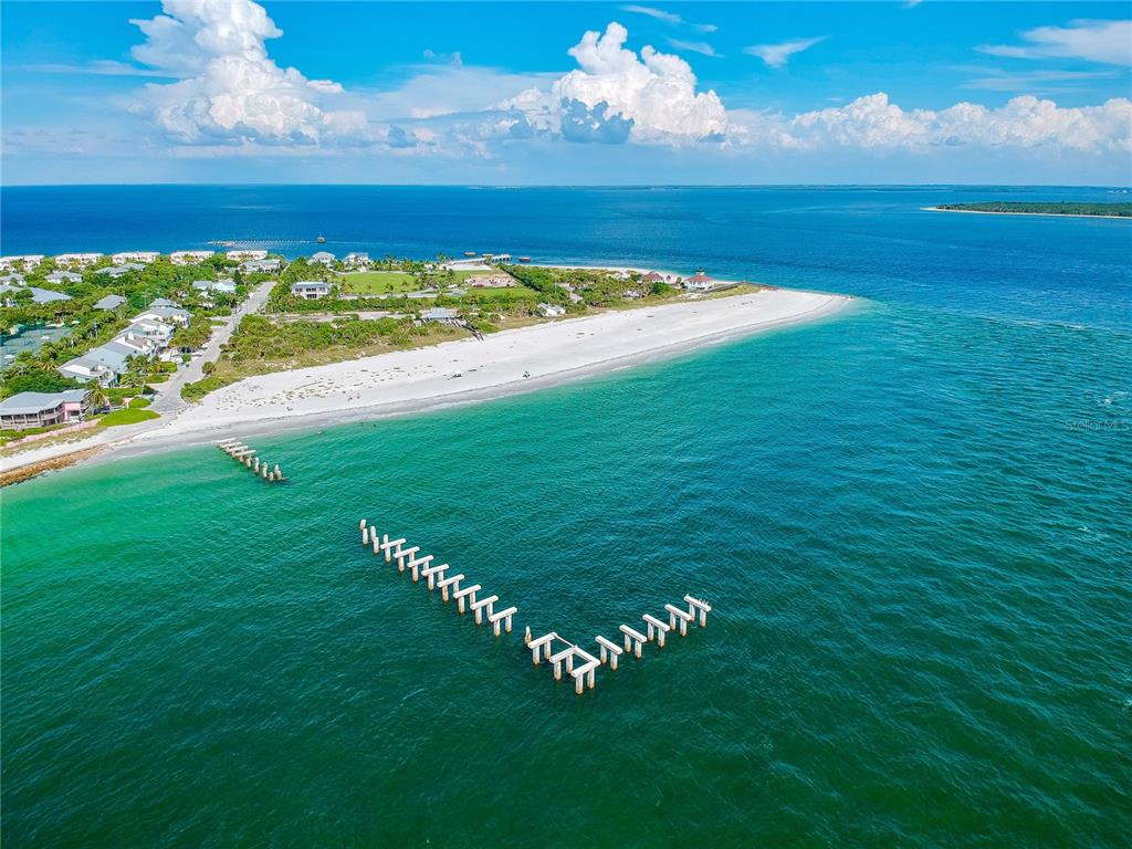 An aerial view shows a sandy beach, coastal homes, and the pilings of a destroyed pier — 285 ROTONDA BOULEVARD W, ROTONDA WEST, FL