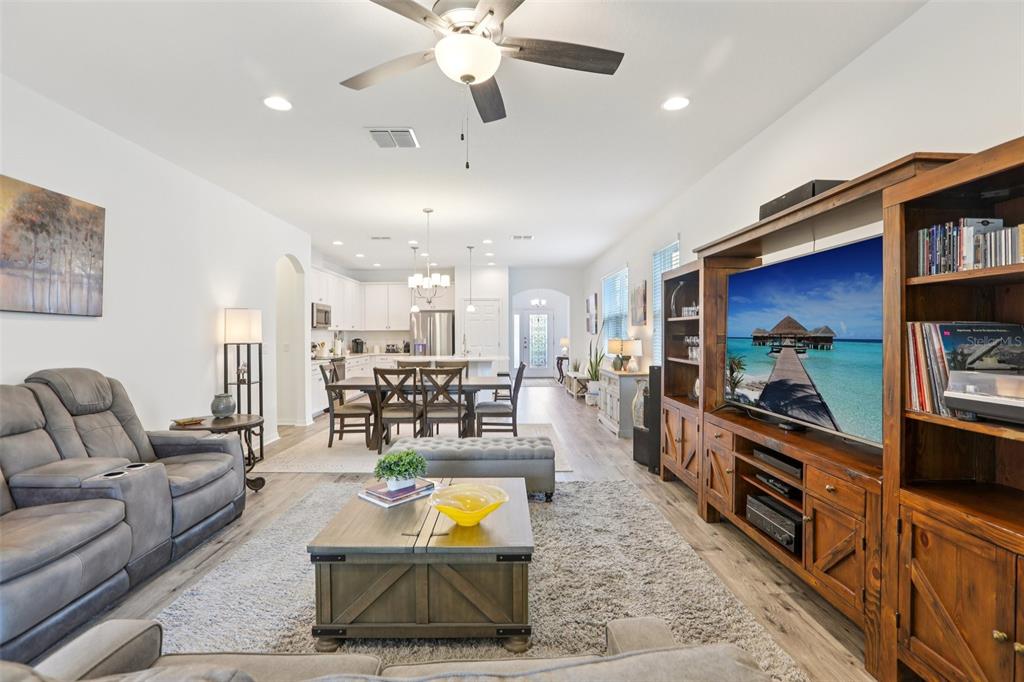 A living room with gray furniture, a wooden entertainment center, and an open-concept kitchen — 7114 GULF CYPRESS AVENUE, LAND O LAKES, FL