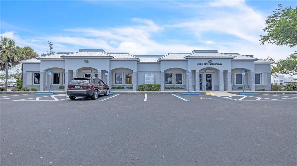 A single-story commercial building with a parking lot and a parked SUV in front — 3300 TAMIAMI TRAIL UNIT 102 B, PORT CHARLOTTE, FL